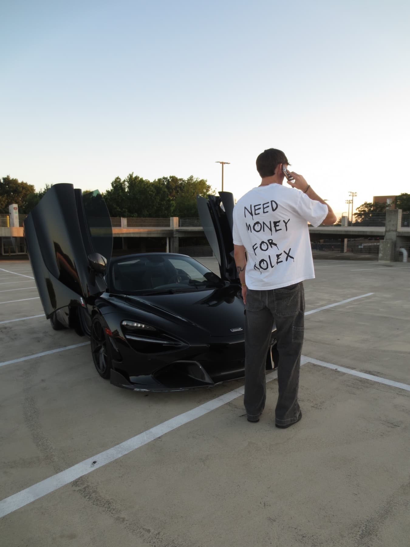 Creator standing beside a black sports car